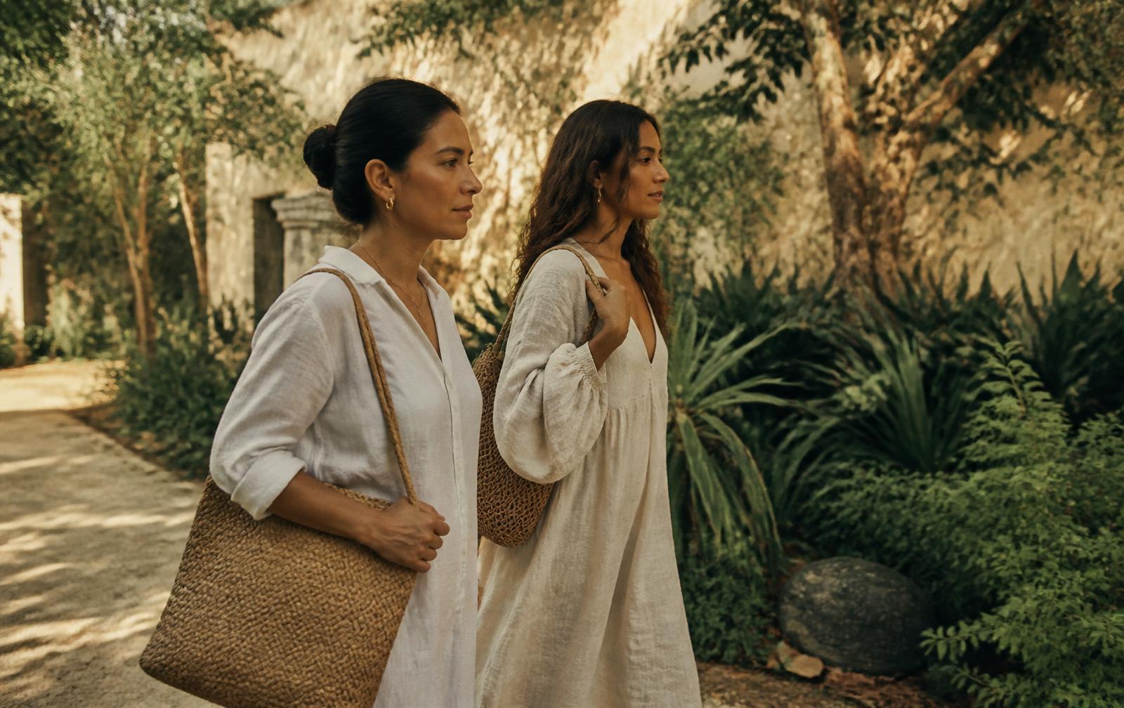 Dos mujeres caminando juntas por un jardín con luz dorada